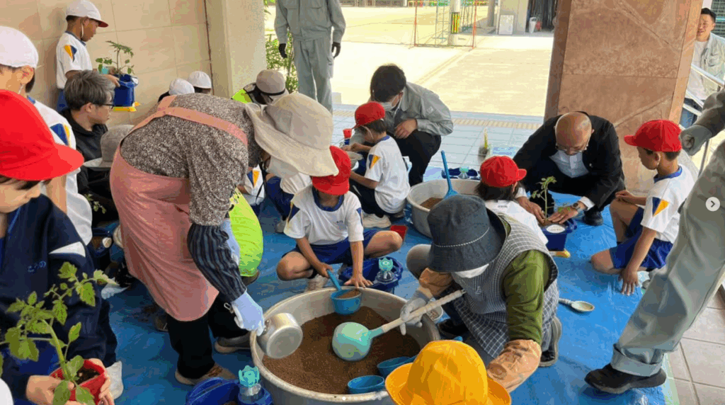 小学校2年生がJA職員や地域ボランティアと一緒にミニトマトなど夏野菜の苗を植える体験の様子